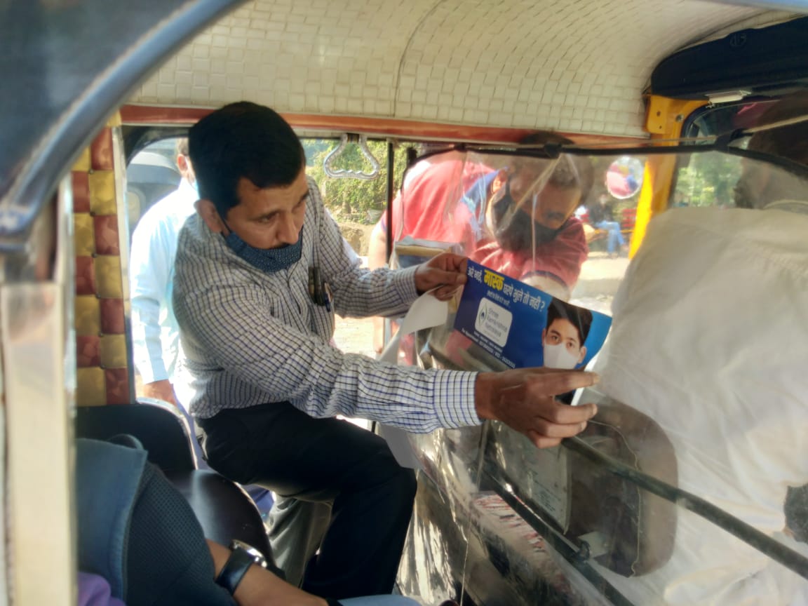 putting wear mask pamphlet in auto rickshaw
